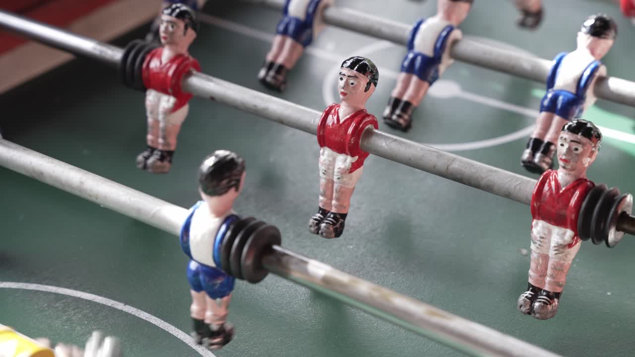 foosball table players lined up mid game in red and blue uniforms under sunlight
