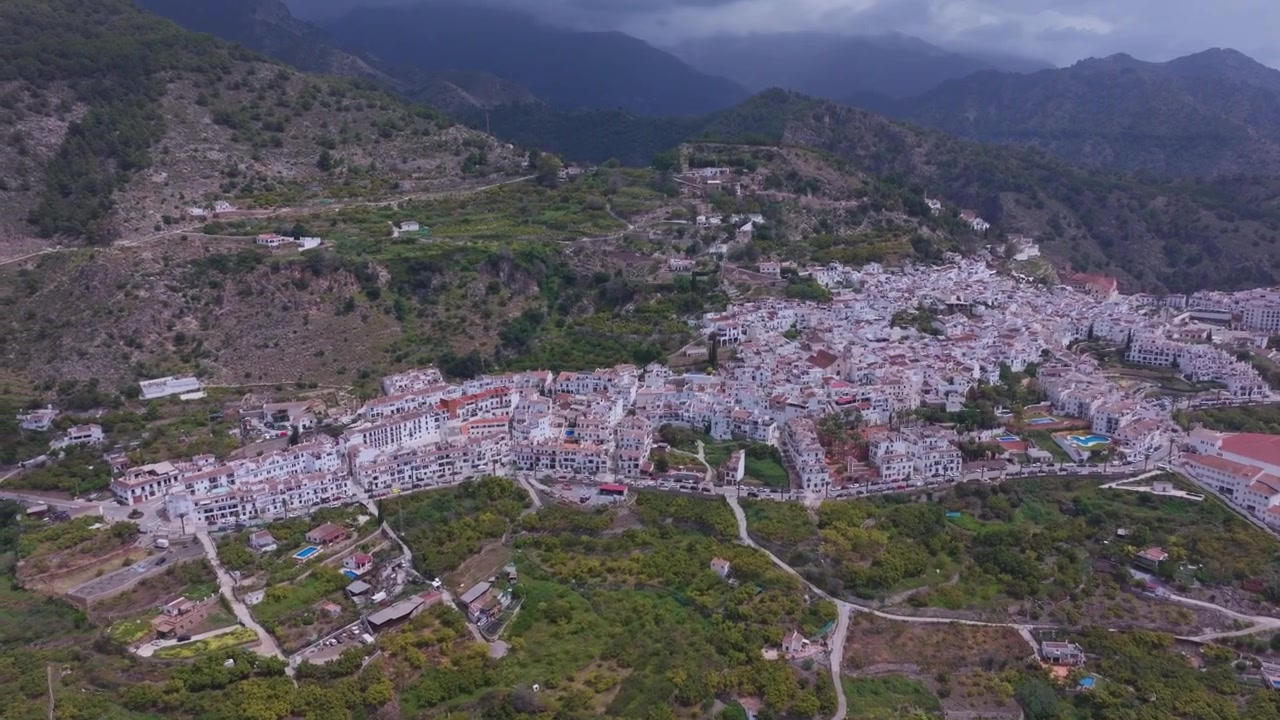 Riprese drone di Frigiliana in Andalusia, Spagna, che rivelano un tranquillo villaggio di montagna imbiancato, circondato da colline aspre e foschia atmosferica.