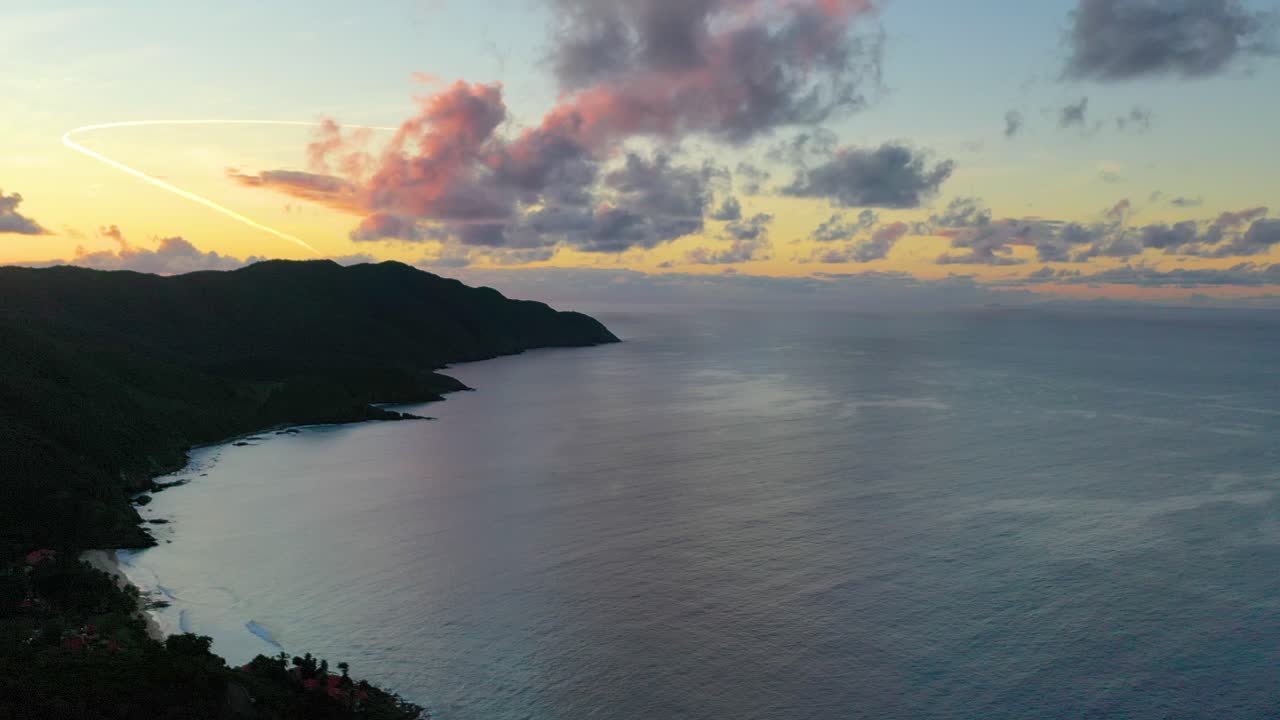 Stunning aerial views reveal pastel skies glowing over St. Croix’s coastline, with a forested peninsula bathed in soft light and calm ocean waters reflecting vibrant colors