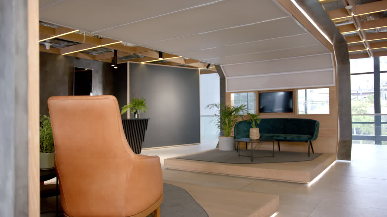 Modern office lounge area with leather chair, green sofa, and indoor plants, copy space