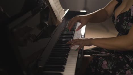 sexy woman with long nails and revealing dress playing piano, close up