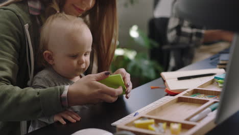 young caucasian business woman mother playing with baby daughter at work playful toddler enjoying loving mom successful motherhood in office workplace