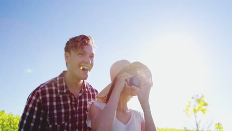 couple taking picture from camera in mustard field