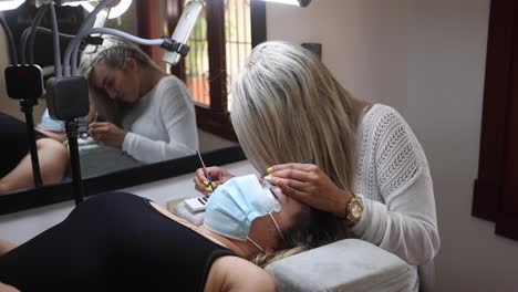 beautician applying eyelashes on face of woman