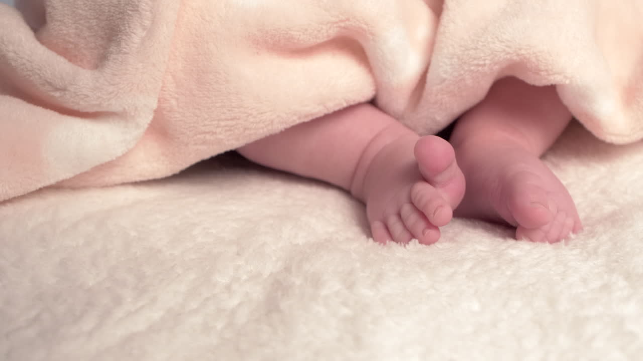 Beautiful Baby newborn is lying in bed and shows hands and feet, mother fandles with baby and covers her up with a cosy coverlet,4k 60p Apple ProRes422, with external Atoms recorder-6