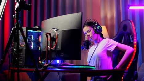 asiatisches mädchen streamer mit rückenschmerzen während des spiels über das netzwerk auf dem personalcomputer. live-stream-videospiel, schreibtisch beleuchtet von rgb-lead-strip-licht