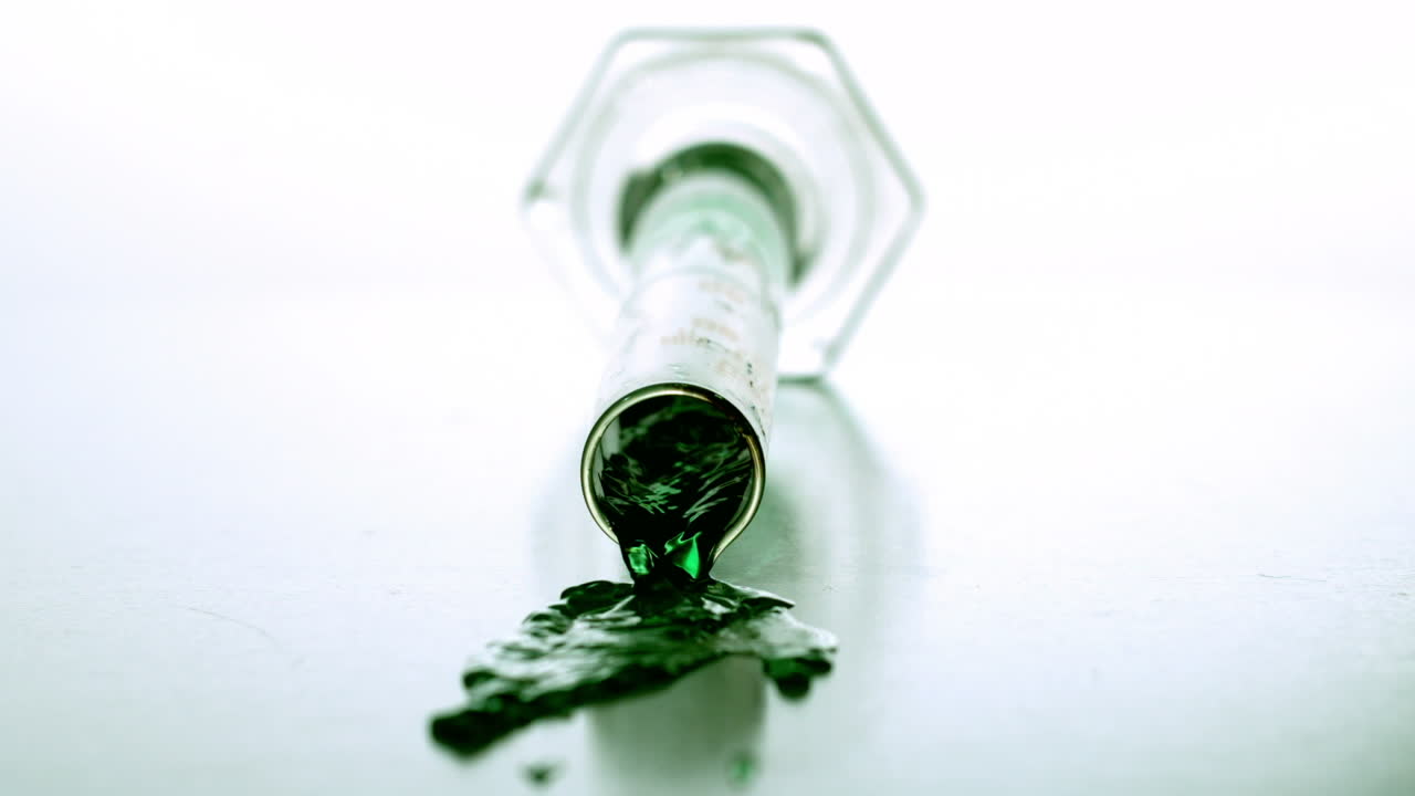 분류 된 실린더가 떨어지고 녹색 액체가 흘러내립니다.