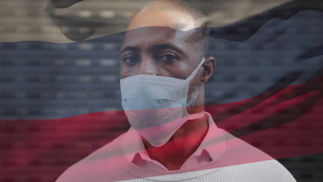 animation of flag of russia waving over african american man wearing face mask in city street