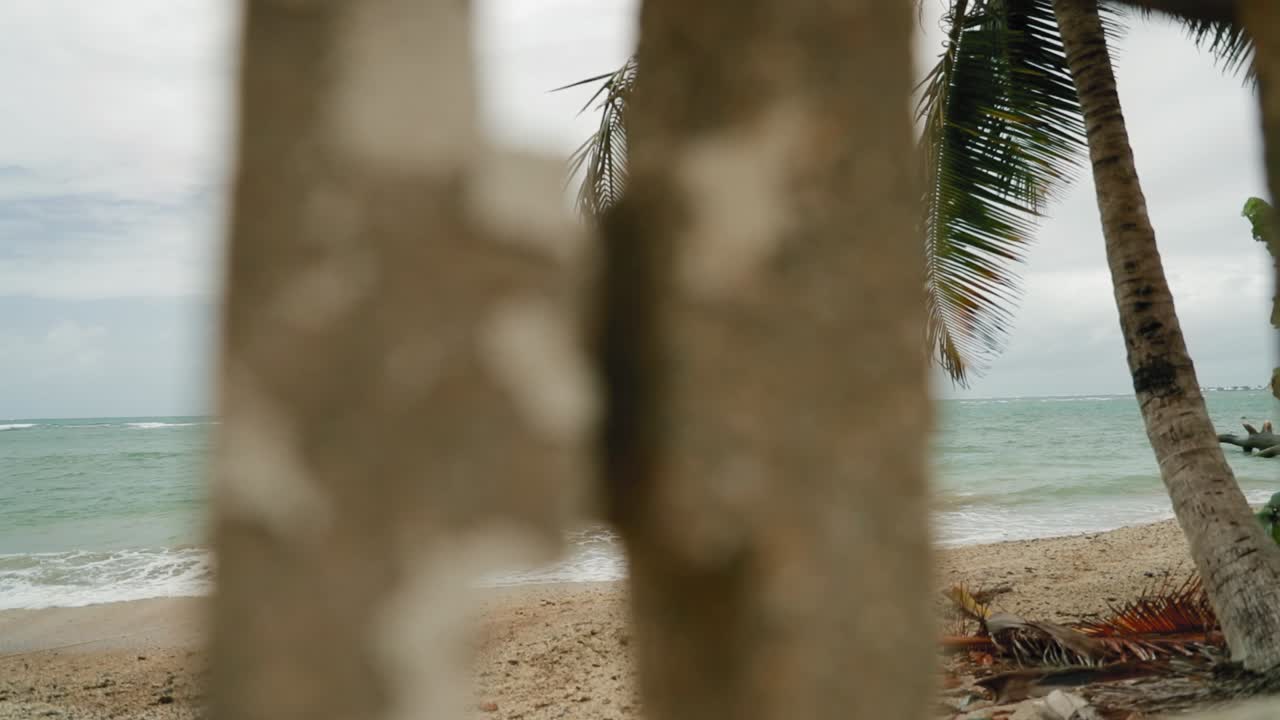 Beautiful blue water beach filmed through breaks in a cinder block wall in Tobago