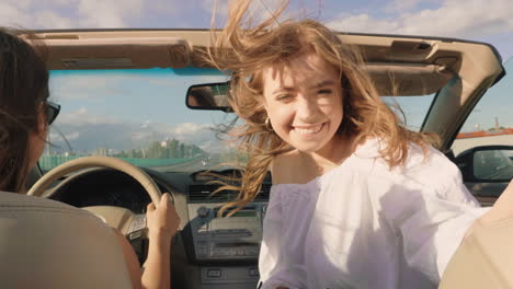 happy friends enjoying a road trip in a convertible