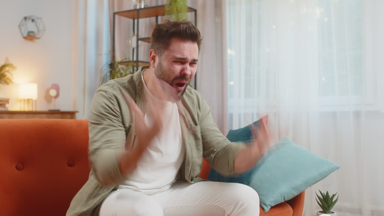 joven triste sintiendo soledad colapso nervioso llorando gritando en el sofá en la sala de estar en casa