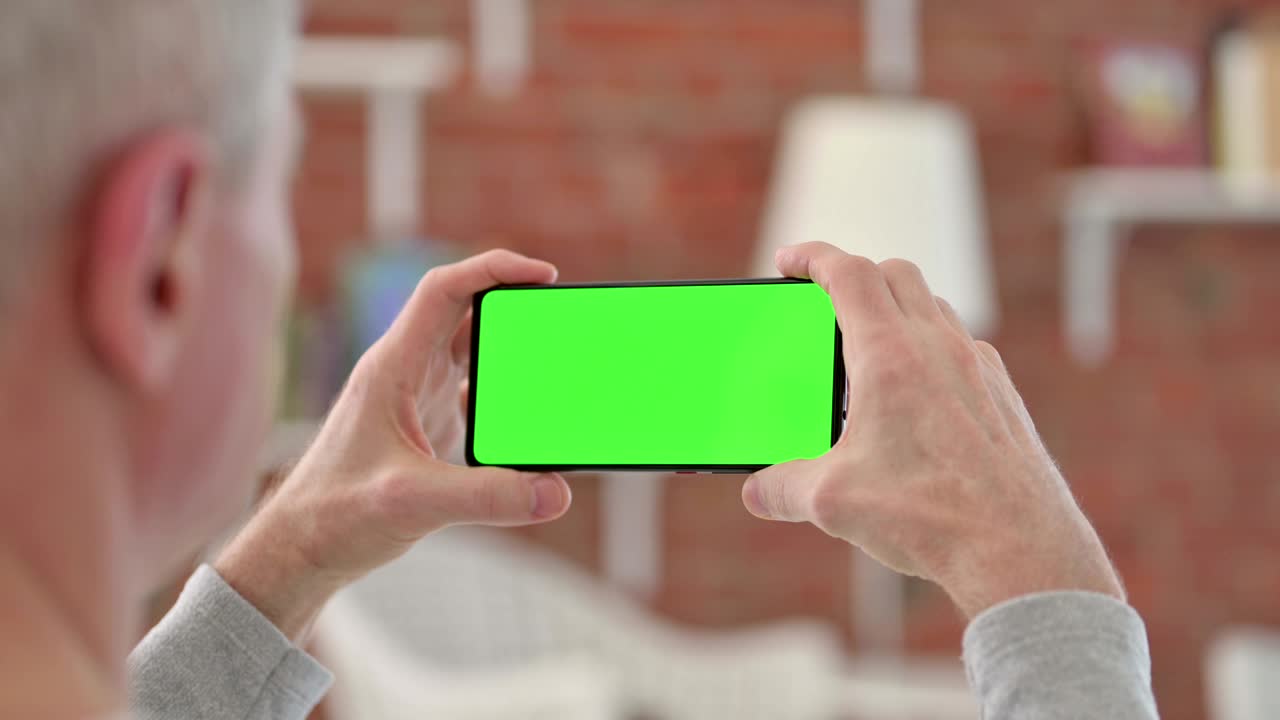 hombre mayor mirando un teléfono inteligente con pantalla cromada