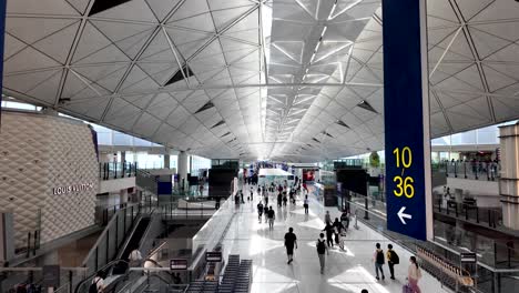 elevated view of the spacious hong kong airport departure concourse featuring travelers and prominent gate numbers, capturing the modern architectural design and bustling atmosphere.