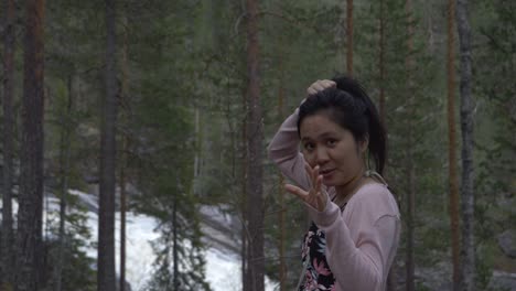 niña jugando con el pelo, sonriendo y girando, en un bosque cerca de un río