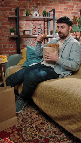 man eating fried chicken on the couch