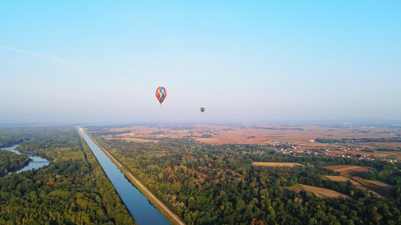 Stunning 4K aerial footage of a drone filming hot air balloons. Flying over farming fields and river. Filmed on a beautiful summer morning. Part of a hot air ballon festival in Prelog, Croatia.
