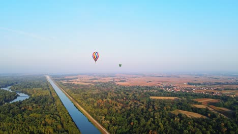 stunning 4k aerial footage of a drone filming hot air balloons. flying over farming fields and river. filmed on a beautiful summer morning. part of a hot air ballon festival in prelog, croatia.
