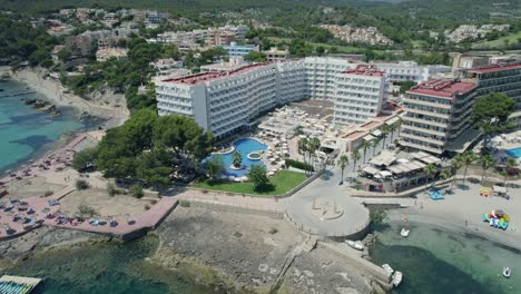 Toma-Cinematográfica-De-Un-Complejo-Hotelero-En-Mallorca-Con-El-Mar-Al-Lado-Y-Una-Gran-Piscina.