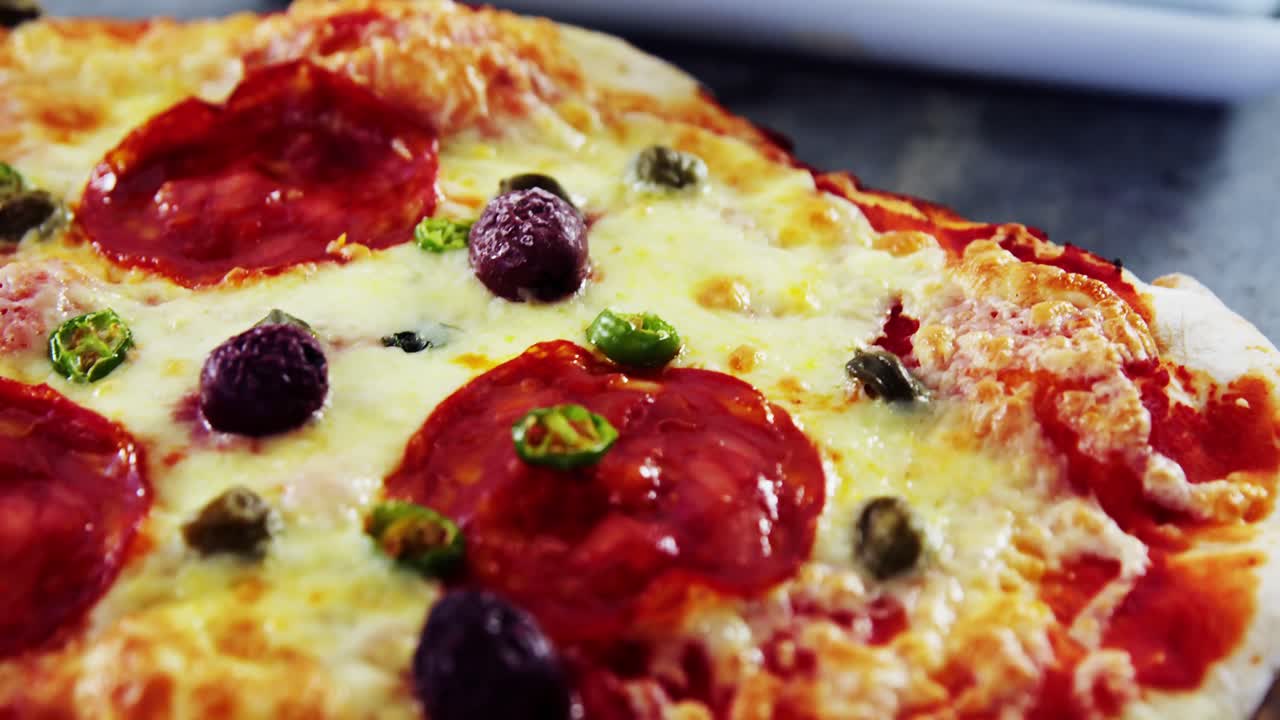 올리브 와 페페로니 가루 를 넣은 구운 피자 가  ⁇ 기 보드 에 제공 된다