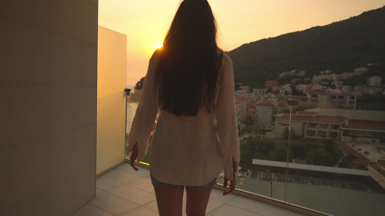 Donna che si gode la vista del tramonto da un balcone