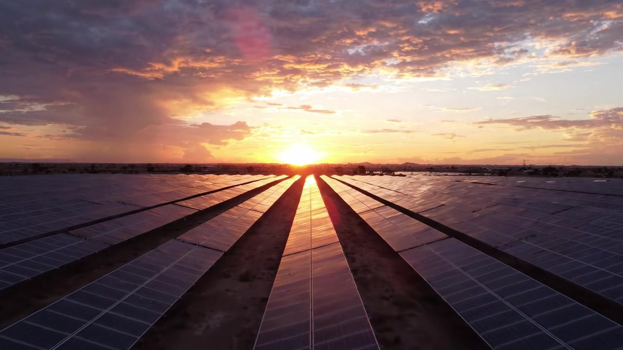 En betagende solnedgang over en stor solcellepark: Oplev den harmoniske blanding af natur og teknologi, når de sidste solstråler oplyser solpaneler i et ørkenlandskab.