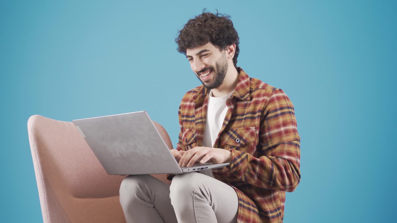 un joven sonriente disfrutando de una comunicación amistosa usando una computadora portátil.