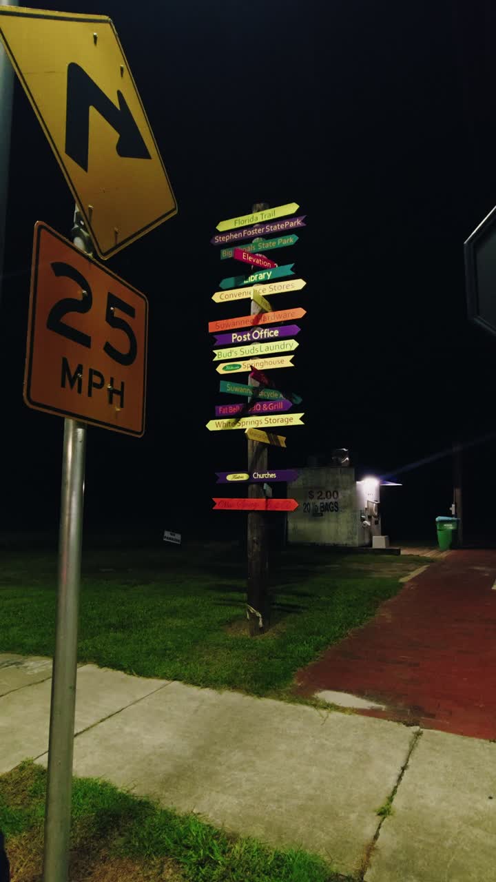 Segnale di avvertimento a forma di diamante giallo illuminato che indica una curva sulla strada e un segnale rettangolare del limite di velocità di 25 MPH. Situato su un tranquillo angolo di strada a White Springs, Florida.