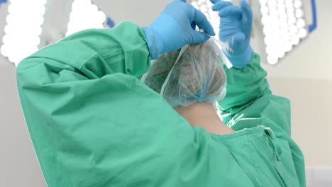 caucasian female surgeon wearing surgical gown and cap in operating theatre, slow motion