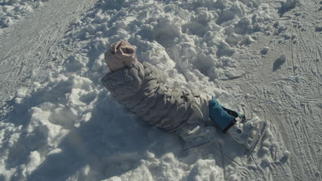 little ice skating girl fallen in the snow watching fellow skaters pass by in lhotka frozen lake in kokorin, czech republic - medium high angle shot