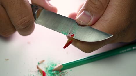 Footage-of-hands-slowly-sharpening-a-pencil-and-some-coloured-pencils-with-a-sharp-knife