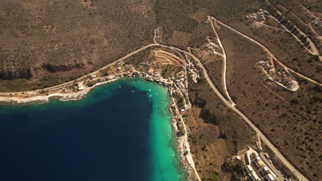 Amplia-Toma-Aérea-En-Un-Caluroso-Día-De-Verano-Junto-A-La-Orilla-Con-Casas-De-Piedra-Y-Botes-Pequeños