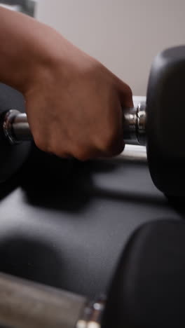 person's hand handling dumbbells