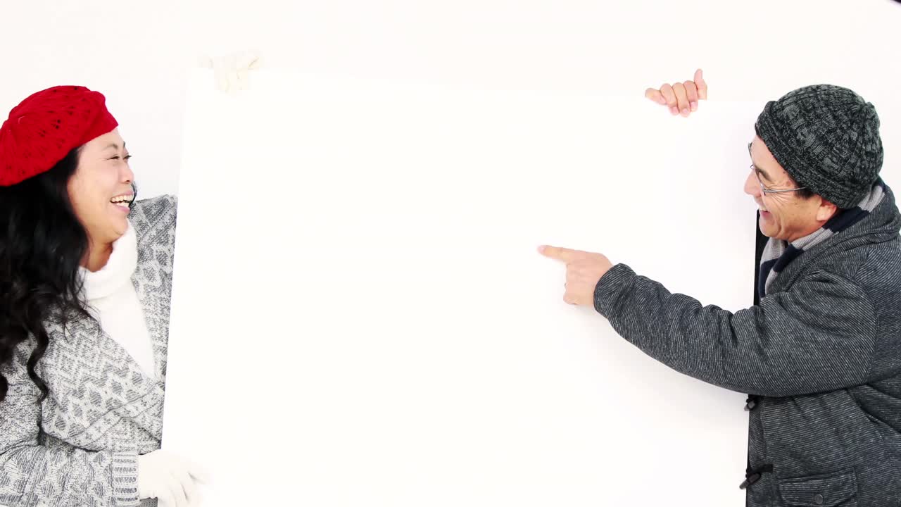 pareja madura sosteniendo y apuntando una pizarra blanca