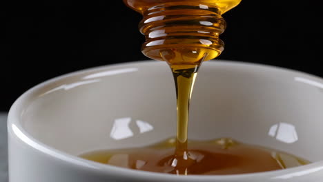 pouring amber oil into a white bowl