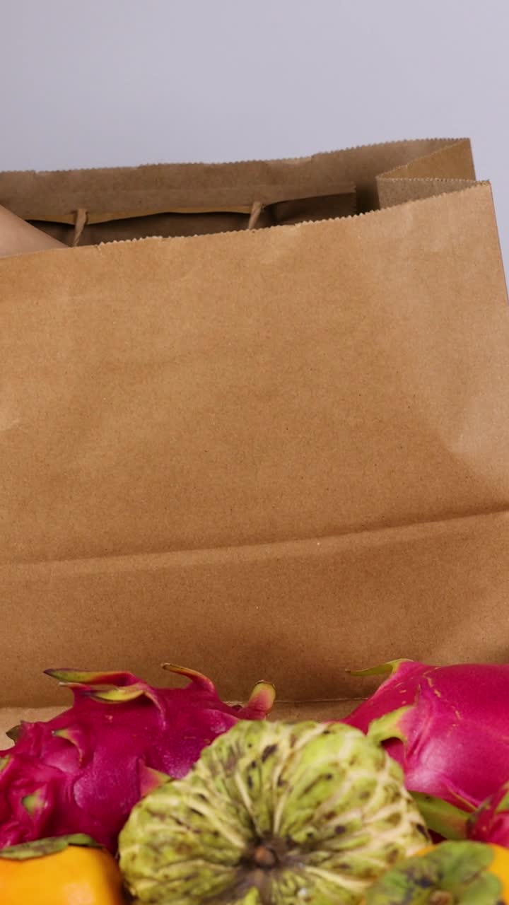 손 은 과일 을 종이 가방 에 넣고 있다