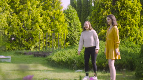 side view of two caucasian young women playing petanque in the park on a sunny day