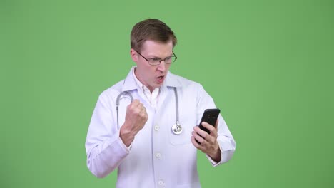 happy doctor using mobile phone while looking excited