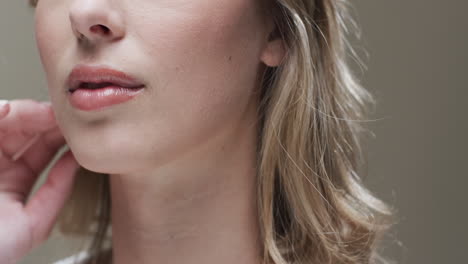 smiling caucasian woman with blond hair and make up touching face, copy space, slow motion