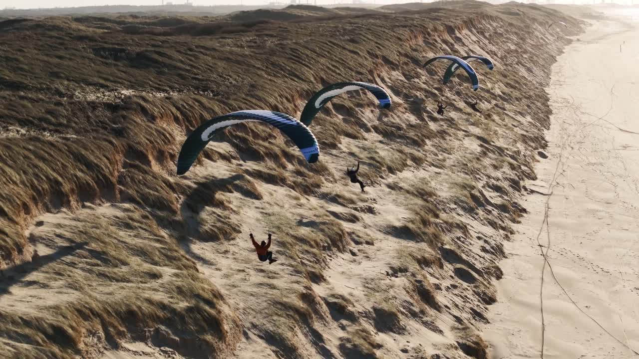 Paragliding over sanddyner og strand