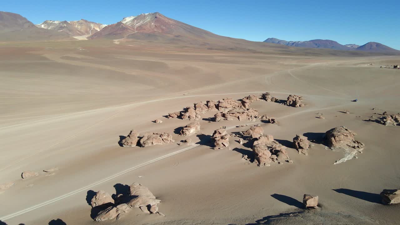 Drone glides across wide red desert plains in Bolivia’s Siloli region with distant rocky hills