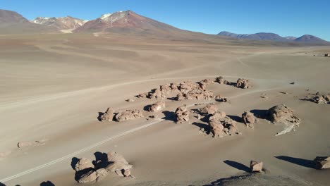 drone glides across wide red desert plains in bolivia’s siloli region with distant rocky hills