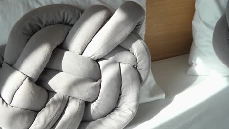 stylish knotted grey pillow on a bed