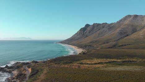 aerial drone view over looking ocean, beach, mountain range and open road