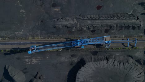 spreader reclaiming coal excavator at a coal terminal near residential area. perfect aerial view flight vertical bird's eye view descending drone