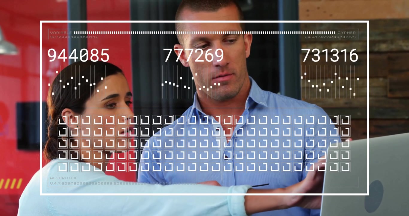 Two colleagues examining laptop in modern tech office, displaying animated graphs and numeric HUD