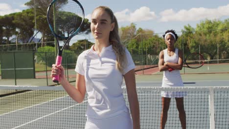 video of diverse female tennis players standing on court and holding rackets