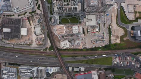 Aerial-birds-eye-overhead-top-down-panning-view-development-project-construction-site.-Busy-road-and-railway-tracks-leading-around.-London,-UK