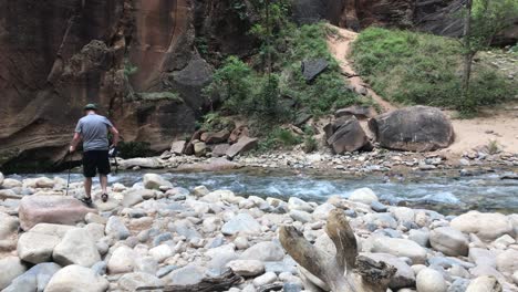 Man-walking-on-stones-with-camera-in-hand