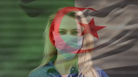 animation of flag of algeria waving over woman wearing face mask during covid 19 pandemic