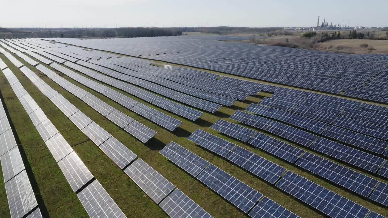 Omfattende solcellepark med rækker af solcellepaneler på en solrig dag, luftfoto